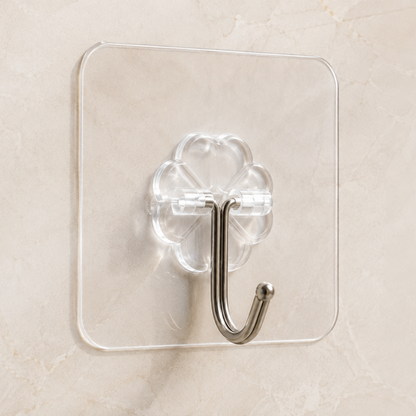 A clear acrylic wall hook with a metallic silver J-shaped hook, mounted on a beige marble-patterned wall.
