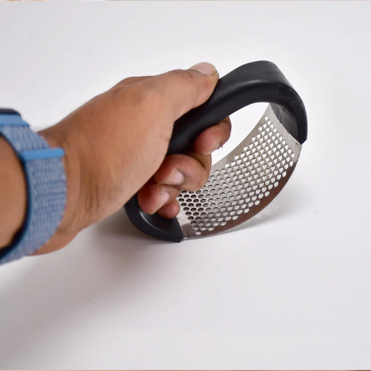 Hand holding a handheld metal grater on a white background